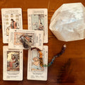 five tarot cards and a pendulum, anchored by a quartz power crystal for expanded spiritual clarity.