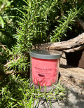Dragon’s Blood vegan soy candle nestled in rosemary bush