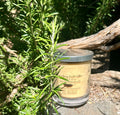 Sandalwood vegan soy candle nestled in rosemary bush