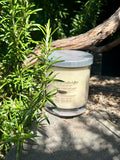 Vanilla Caramel vegan soy candle nestled in rosemary bush