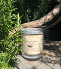 Ylang Vanilla vegan soy candle nestled in rosemary bush